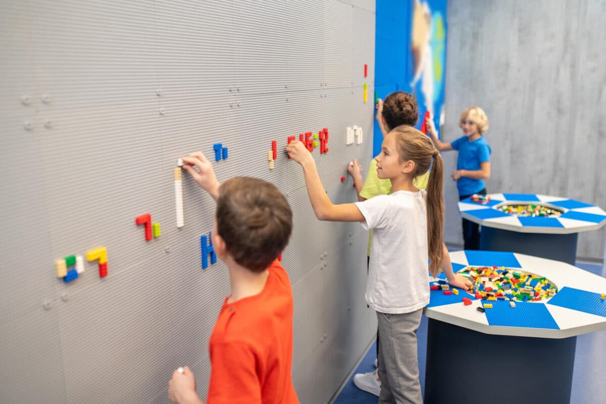 Construire ensemble, penser autrement : des enfants collaborant sur un mur de LEGO pour explorer de nouvelles réalités et perspectives