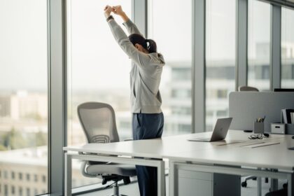 Personne debout près d'un bureau dans un open space lumineux, étirant les bras en pause active